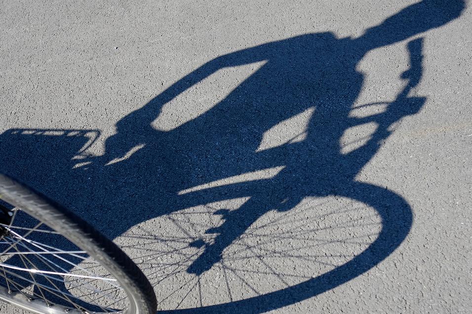 Schattenspiel eines Fahrradfahrenden auf der Straße