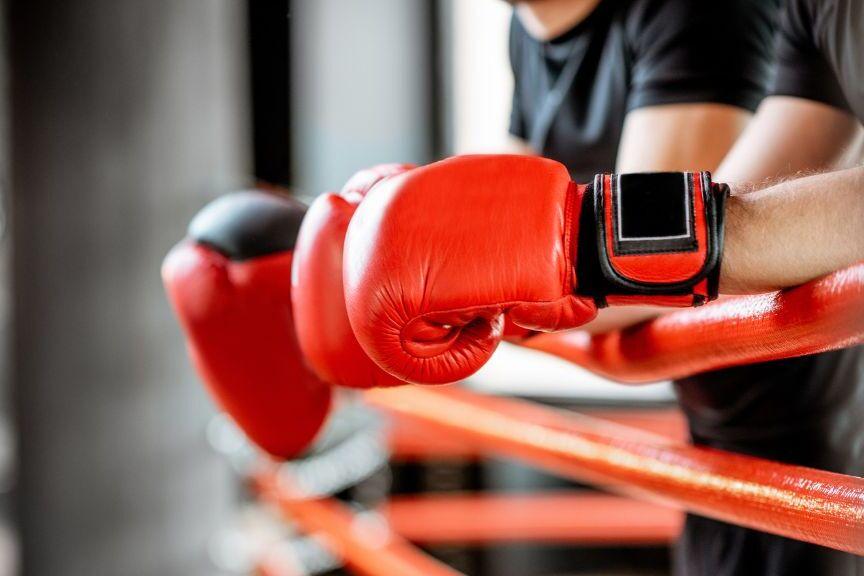 Boxer*in lehnen mit Boxhandschuhen auf Ringseile