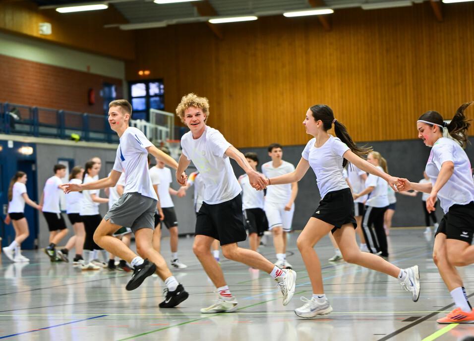 Jugendliche gemeinsam Hand in Hand in der Sporthalle
